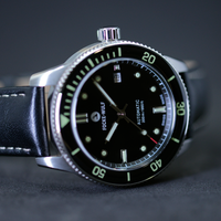 Dive watch with black face and green accents on a dark background