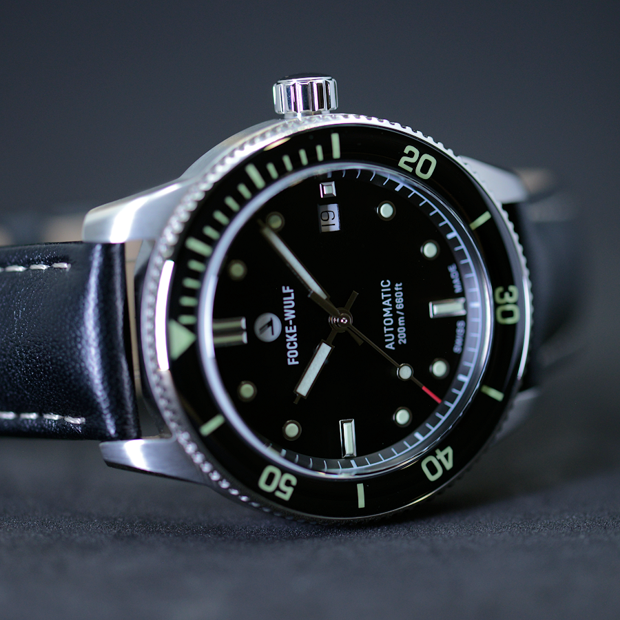 Dive watch with black face and green accents on a dark background