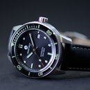 Watch with black dial and green accents on a dark background