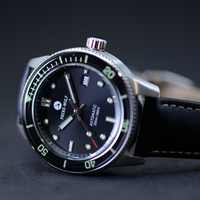 Watch with black dial and green accents on a dark background